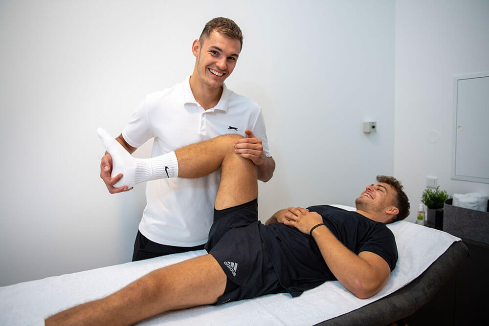 Physiotherapeut Michael Petautschnig mit Kunden am Beinstrecker bei Knieschmerzen